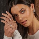 Woman wearing multiple rings on her hand with a neutral background